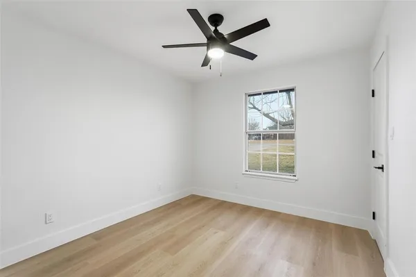 an empty room with a window and a ceiling fan