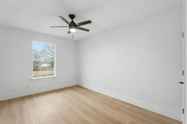 an empty room with a window and a ceiling fan