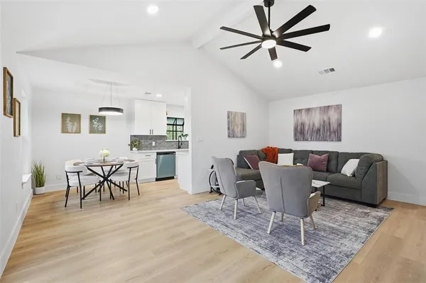 a living room with furniture a dining table and paintings on the wall with wooden floor