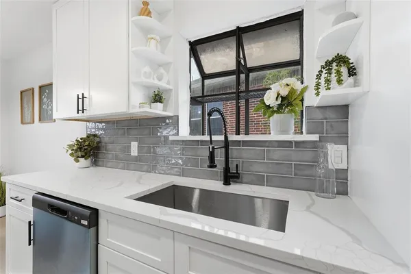 a kitchen with stainless steel appliances a sink a potted plant on the counter and cabinets