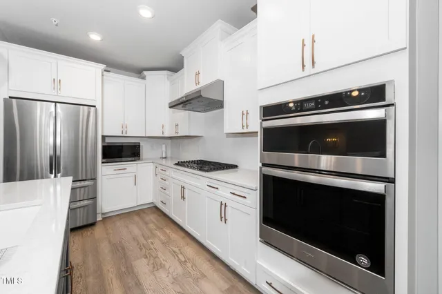 a kitchen with stainless steel appliances white cabinets a stove top oven and refrigerator