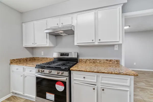 a kitchen with granite countertop a stove sink and cabinets