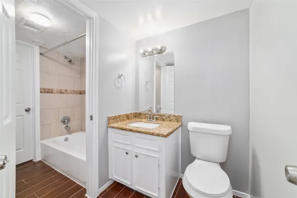 a bathroom with a granite countertop toilet a sink and bathtub