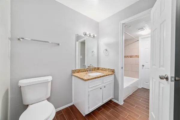 a bathroom with a granite countertop toilet a sink and a mirror