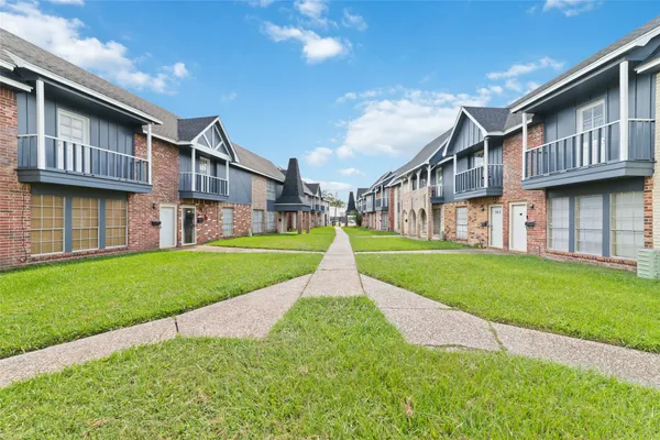 a view of a house with a big yard plants and large tree