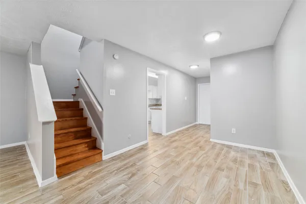 a view of empty room with wooden floor and stairs