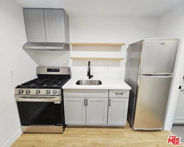 a kitchen with a stove top oven and refrigerator