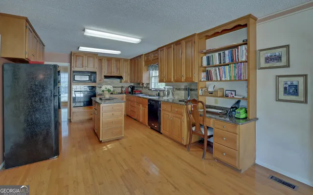 a kitchen with stainless steel appliances kitchen island granite countertop a refrigerator and a stove top oven