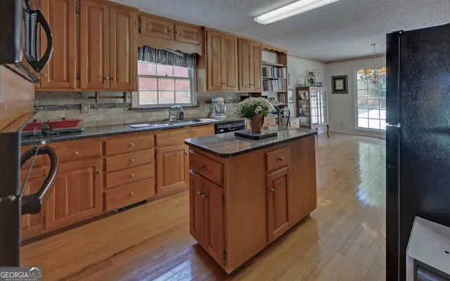 a kitchen with kitchen island granite countertop wooden cabinets and white appliances