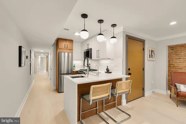 a kitchen with a refrigerator a sink dishwasher a dining table and chairs with wooden floor