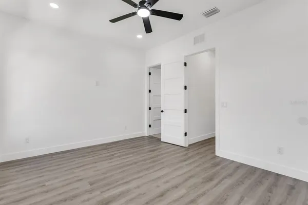 an empty room with wooden floor and windows