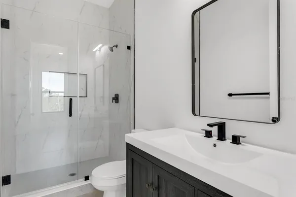 a bathroom with a sink toilet a mirror and shower