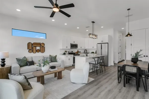 a living room with furniture kitchen view and a chandelier