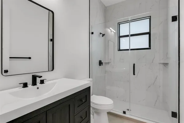 a bathroom with a sink toilet a mirror and shower