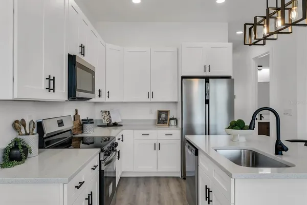 a kitchen with stainless steel appliances granite countertop a sink stove refrigerator and cabinets