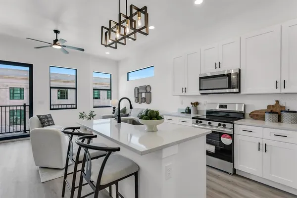 a kitchen with stainless steel appliances granite countertop a stove top oven a sink a dining table and chairs with wooden floor