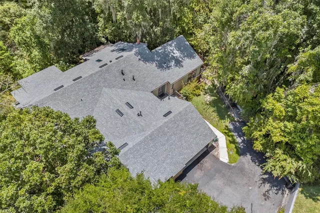 an aerial view of a house with a yard and large tree