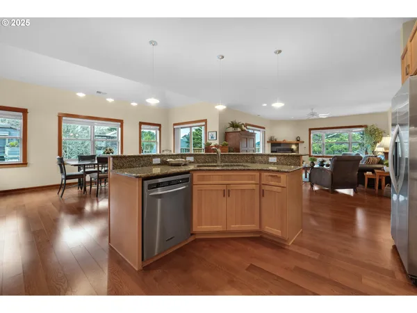 a kitchen with stainless steel appliances granite countertop a stove top oven a sink a dining table with wooden floor
