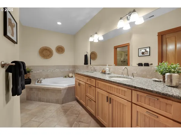 a bathroom with a granite countertop double vanity sink a mirror and a bathtub