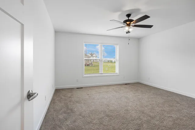 a view of an empty room and chandelier fan