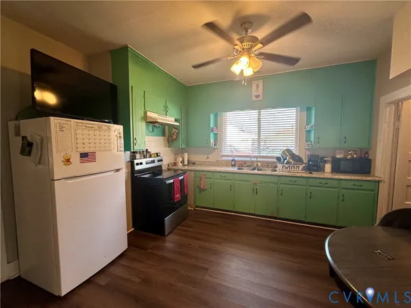 a kitchen with a refrigerator a stove a sink dishwasher and a dining table with wooden floor