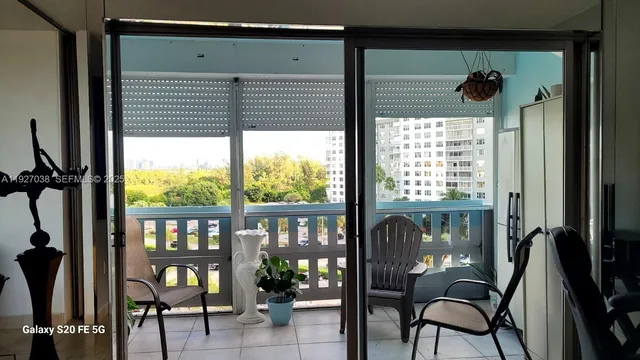 a view of a porch with a table and chairs and a floor to ceiling window