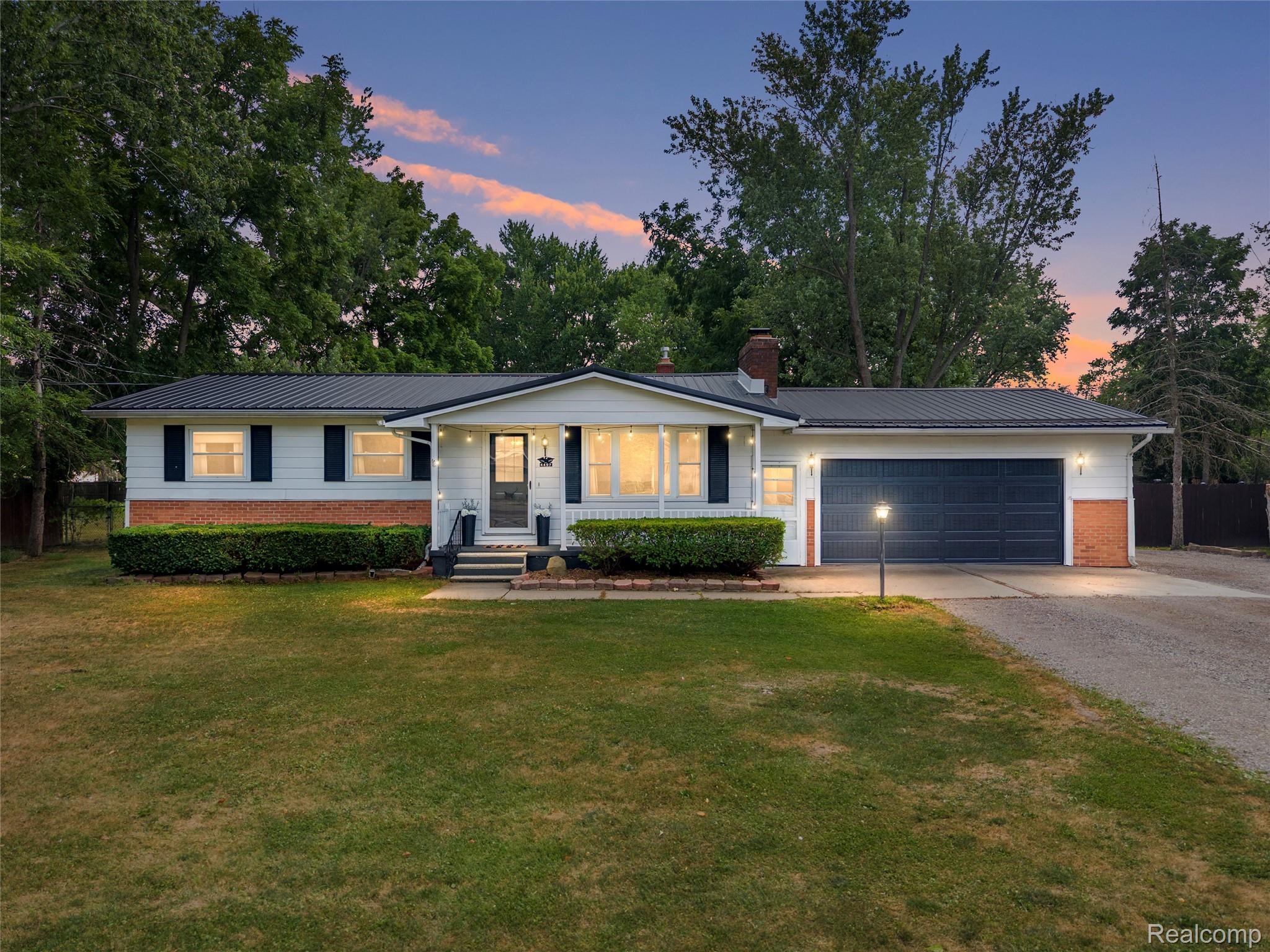 4497 Reid Road Swartz Creek, MI 48473 - Photo 1 of 31 Ranch-style residence featuring a dark metal roof, white siding, and partial brick facade