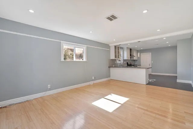 a view of kitchen and empty room with wooden floor