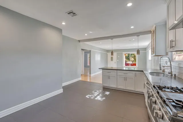 a large kitchen with stainless steel appliances a large counter top a stove and a sink