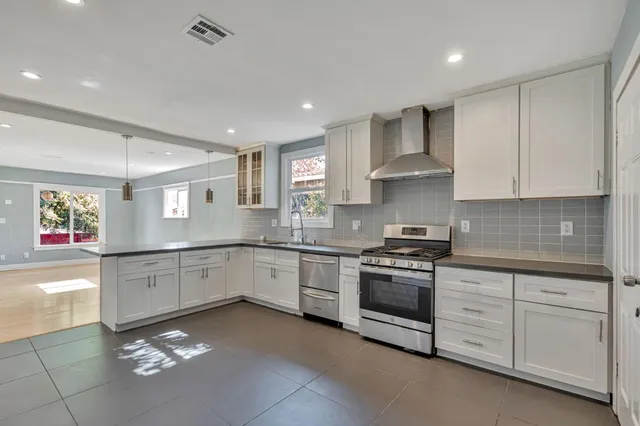 a large kitchen with stainless steel appliances granite countertop a stove and a sink