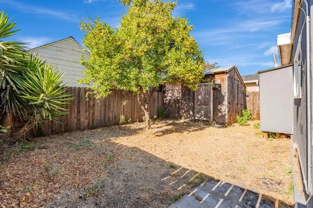 a backyard of a house with large trees and wooden fence