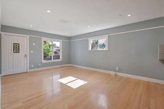 an empty room with wooden floor and windows