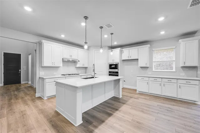 a large kitchen with cabinets wooden floor and stainless steel appliances