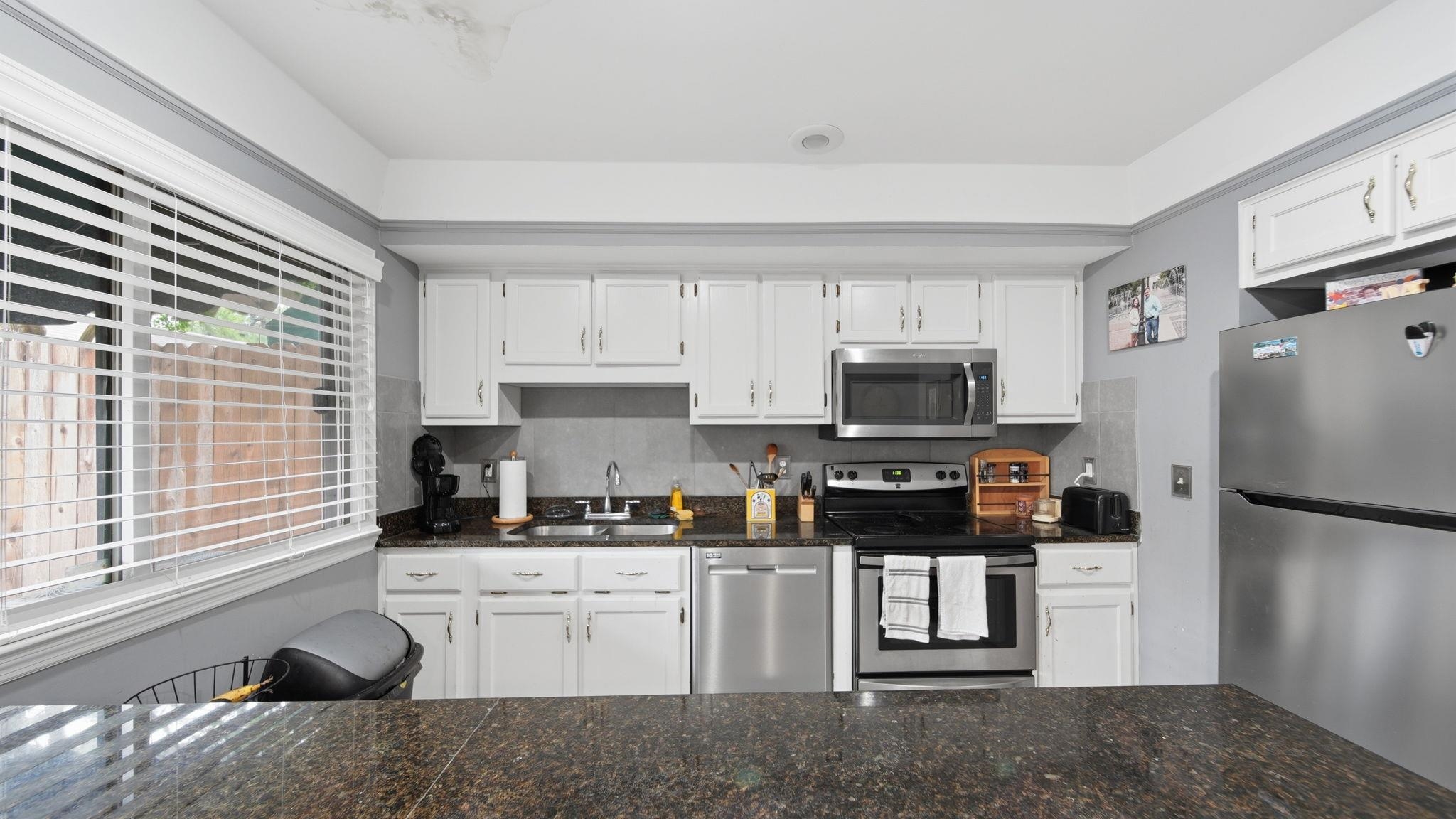 5866 Roxbury Drive, Unit 5866 Memphis, TN 38119 - Photo 9 of 20 Kitchen featuring white cabinetry, dark stone countertops, and stainless steel appliances including a refrigerator, dishwasher, oven, and microwave