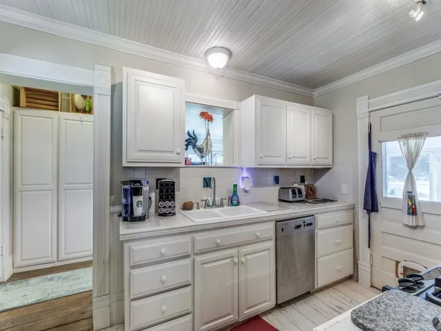 a kitchen with a sink dishwasher and cabinets with wooden floor