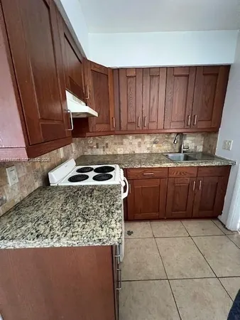 a kitchen with granite countertop a sink a stove and cabinets