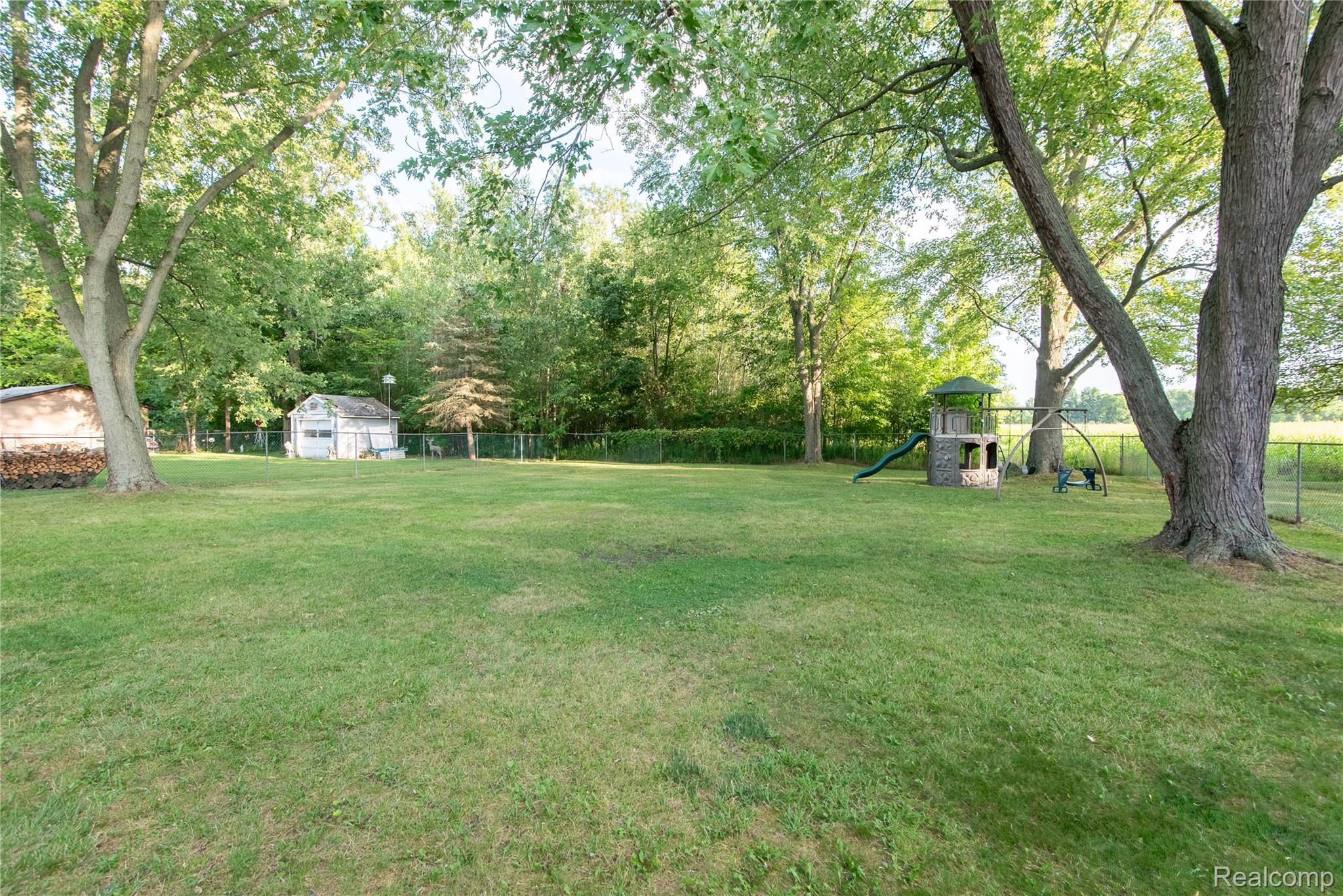 4395 Regency Road Swartz Creek, MI 48473 - Photo 54 of 67 Expansive green lawn with mature trees and a chain-link fence