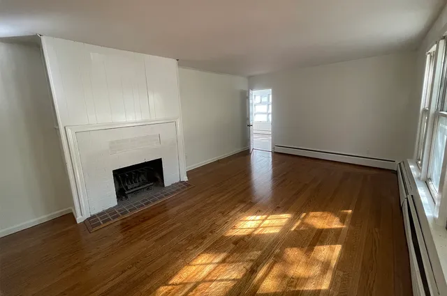 a view of a livingroom with wooden floor and a fireplace