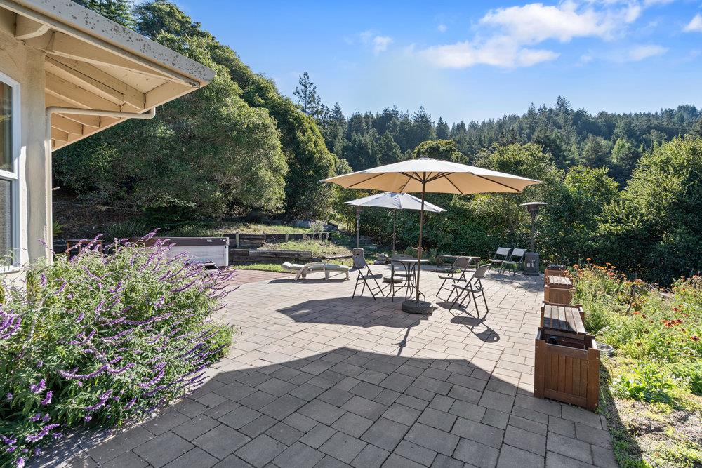 4760 Soquel Creek Road Soquel, CA 95073 - Photo 22 of 29 a view of a patio with chairs and a table and chairs under an umbrella
