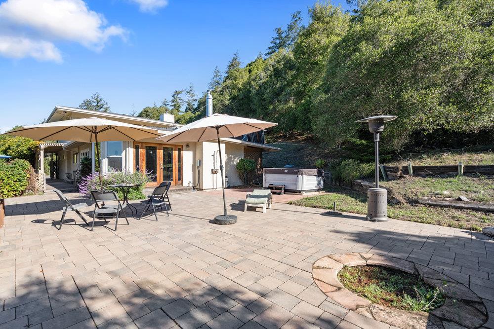 4760 Soquel Creek Road Soquel, CA 95073 - Photo 24 of 29 a view of a patio with table and chairs under an umbrella with a barbeque grill and plants