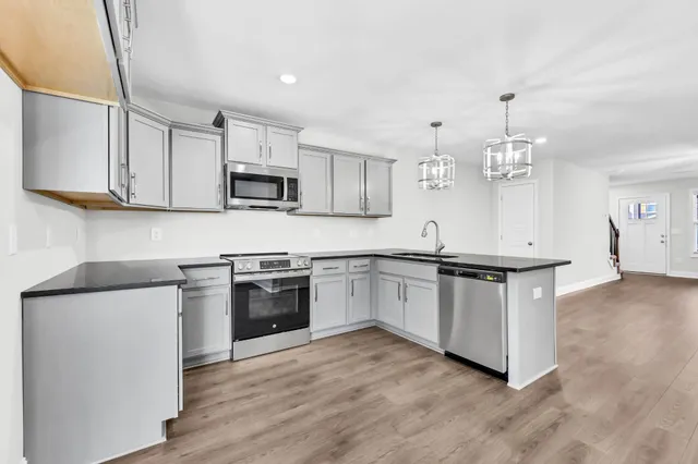 a kitchen with stainless steel appliances granite countertop a stove a sink and a microwave