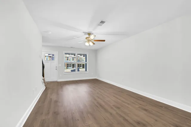 a view of an empty room with wooden floor and a window