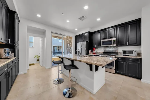 a kitchen with granite countertop a stove refrigerator and cabinets