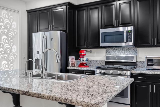a kitchen with granite countertop a refrigerator and a stove top oven