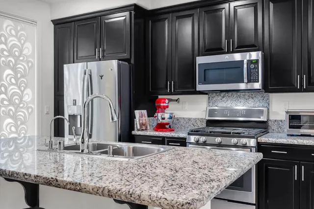a kitchen with granite countertop a refrigerator and a stove top oven