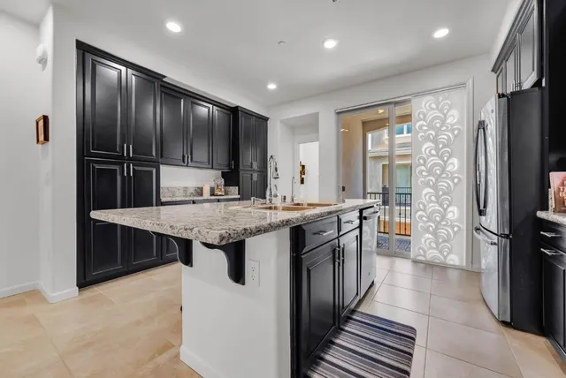 a kitchen with kitchen island granite countertop a sink stove and refrigerator