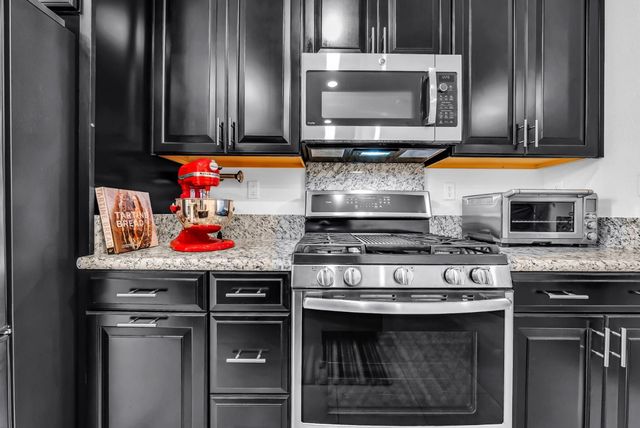a kitchen with stainless steel appliances granite countertop a stove microwave and sink