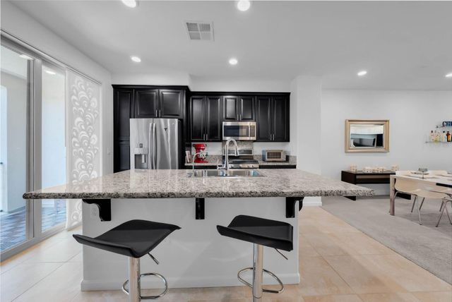 a large kitchen with granite countertop a counter space chairs stainless steel appliances and cabinets