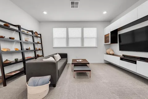 a living room with furniture a flat screen tv and a window