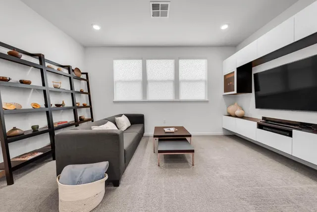 a living room with furniture a flat screen tv and a window